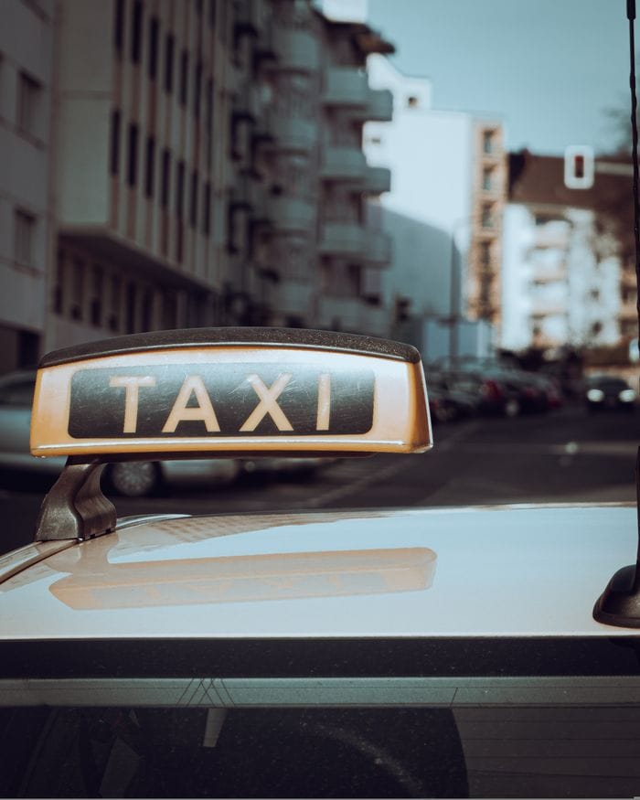 The Art of Drawing Readers In: Your attractive post title goes here Close-up of a taxi sign on a car with city buildings in the background.